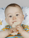 Tämä on esimerkki kuvasta, jossa lapsella on käsissään lelu ja taustalla näkyy tyyny.